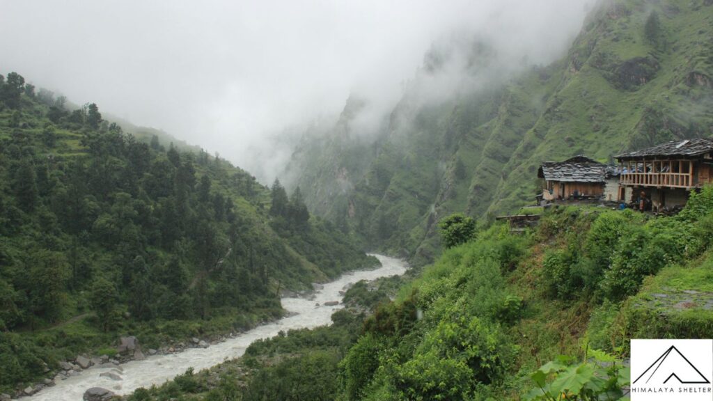 old houses and river with fog in har ki dun valley trek